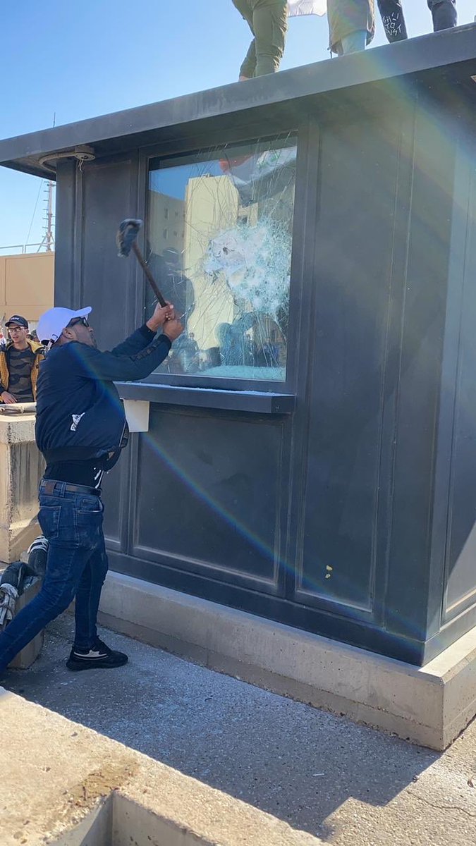 Pro-Hezbollah protesters smashing windows in security box near walls of U.S. Embassy complex in Green Zone Baghdad 